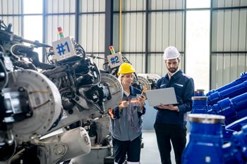 Engineer holding laptop observing production in an automotive parts factory