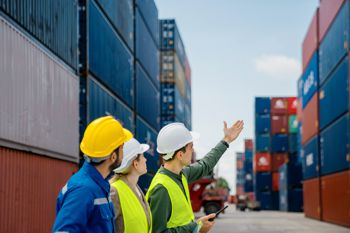 Foreman of a group of people in control of loading shipping container boxes to truck for the logistics of Import/Export