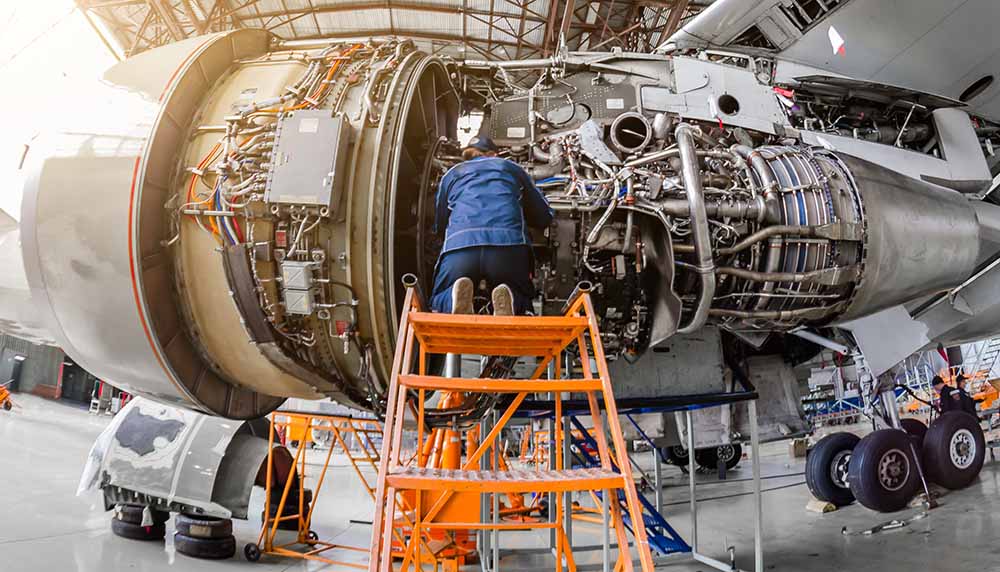Aircraft engine maintenance being conducted in a large hangar.