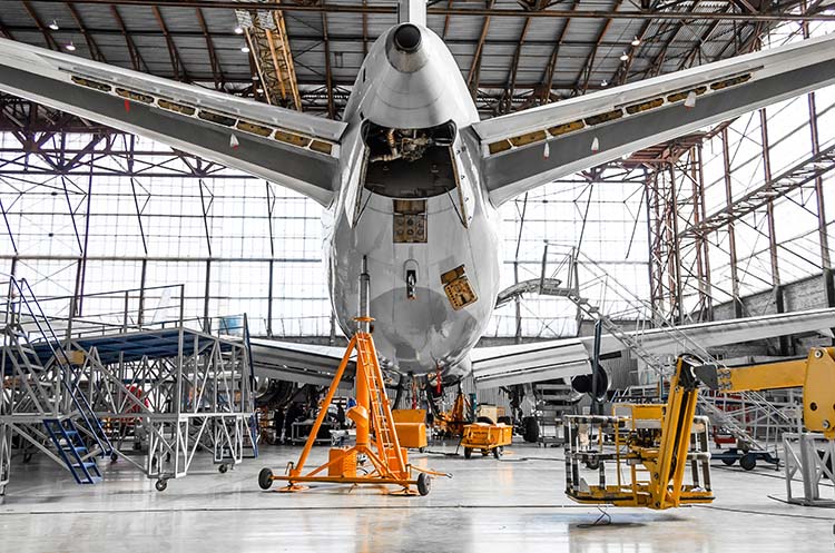 Aircraft undergoing maintenance inside a large hangar.