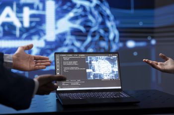 Two hands pointing towards a laptop with AI animations in the background